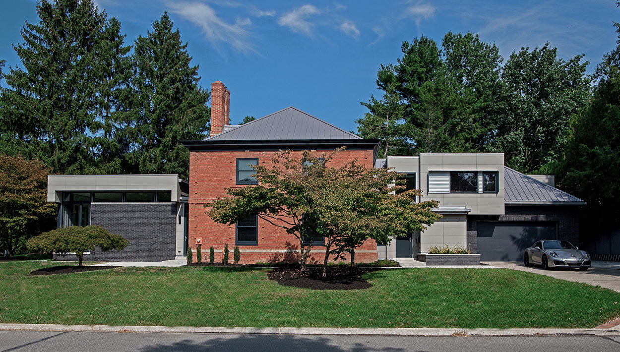 Exterior of existing brick home flanked by two modern additions